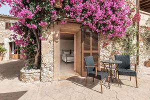 un patio con mesa, sillas y flores rosas en Finca Es Torrent, en Campos