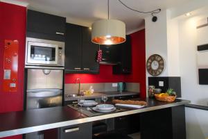 a kitchen with black cabinets and a red wall at Le Bobillot By ApiRent #Central #Terrasse #Wifi #Clim in Cannes