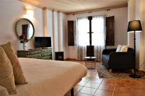 ein Schlafzimmer mit einem Bett, einem Stuhl und einem Spiegel in der Unterkunft Hotel Rural Alfajía de Antonio in Capileira