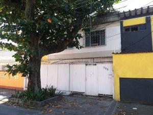 un edificio blanco y amarillo con un árbol delante de él en Casa Branca 355 Familiar en Río de Janeiro