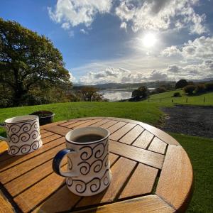 due tazze di caffè sedute su un tavolo di legno di Shepherds Hut, Conwy Valley a Conwy