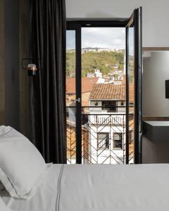 ein Schlafzimmer mit einem Bett und einem großen Fenster in der Unterkunft Triumf Hotel in Prizren