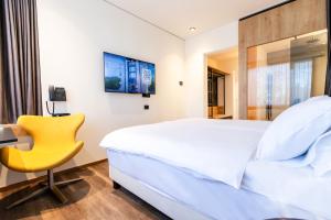 een slaapkamer met een bed en een gele stoel bij Hotel Lonca - Superior in Škofja Loka