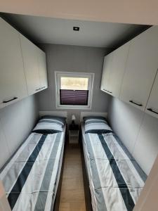 2 camas en una habitación pequeña con ventana en Ferienhaus Aurora, Sauna, Seeblick, angeln en Twist