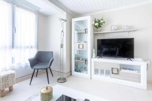 a white living room with a television and a chair at Old Port, apartamento con vistas al puerto in Bermeo