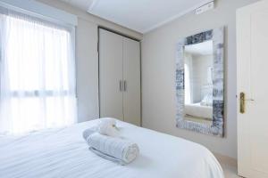 a white bedroom with a bed with towels on it at Old Port, apartamento con vistas al puerto in Bermeo