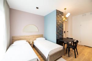 two beds in a room with a desk and a table at B85 Suites in Warsaw
