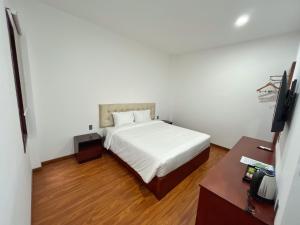 Schlafzimmer mit einem weißen Bett und einem Schreibtisch in der Unterkunft Ban Me Central Hotel 2 in Buon Ma Thuot