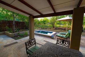 a patio with a table and chairs and a pool at Bee-Eater Cottage in Hoedspruit