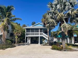 a house on the beach with palm trees at Escape to an island adventure! Free bikes & beach items in Anna Maria