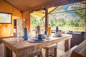 una mesa de madera con tazas y platillos. en Tente lodge Jacuzzi privatif en pleine nature, en Thiel-sur-Acolin
