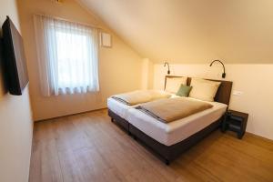 1 dormitorio con cama, ventana y TV en Biohof Döbler Ferienwohnungen, en Brackenheim