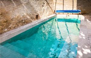 einen Pool mit blauem Wasser vor einer Ziegelwand in der Unterkunft Nice Home In Raix With Wi-fi 