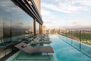Tri Hotel Premium Itapema في ايتابيما: مسبح مع كراسي جلوس على سطح المبنى