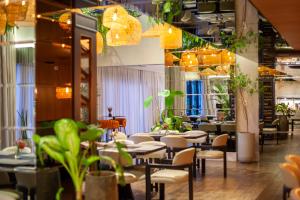 Tri Hotel Premium Itapema في ايتابيما: غرفة طعام مع طاولات وكراسي وأضواء