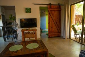 sala de estar con mesa de madera y TV en Bee-Eater Cottage, en Hoedspruit