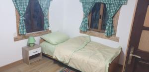 a small bedroom with a bed and two windows at Oaza Mister D 