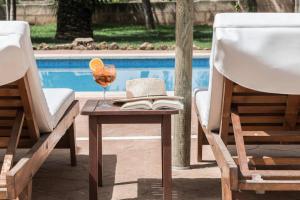 a glass of wine and a book on a table next to two chairs at Finca Es Torrent in Campos