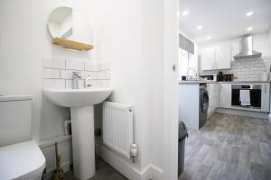 a white bathroom with a sink and a kitchen at K Suites - Seymour Street in Mountain Ash