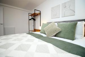 a bedroom with a bed with green and white pillows at K Suites - Seymour Street in Mountain Ash
