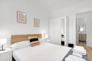 a white bedroom with a large bed and a chair at Palmereta in Sagunto