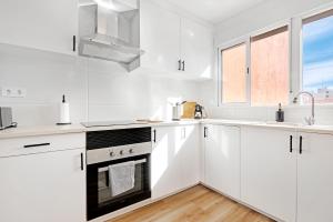 a white kitchen with white appliances and a window at Palmereta in Sagunto