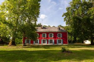 una casa roja con un árbol delante en La Maison Des Pilotes - Circuit - Luxueux - 15 pers - Rêve au Mans, en Mulsanne