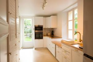 una cocina con armarios blancos y una ventana en La Maison Des Pilotes - Circuit - Luxueux - 15 pers - Rêve au Mans, en Mulsanne