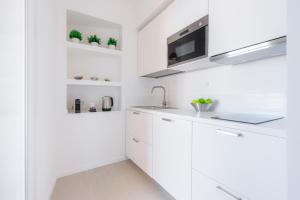 a white kitchen with white cabinets and a sink at Puolo Seaside Apartment 2 in Massa Lubrense