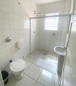a white bathroom with a toilet and a sink at Hotel Cidade De Bauru in Bauru