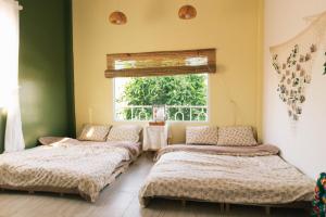 two beds in a room with a window at Phòng Chôm Chôm (Rambutan Room) - Nhà Mơ Homestay Bến Tre in Ben Tre