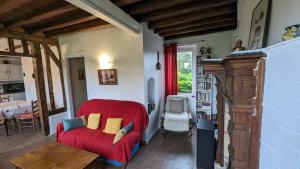 a living room with a red couch and a table at Gîte chez Loupi in Épaignes