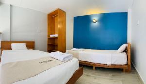 2 camas en una habitación con una pared azul en La Quinta Loft Apartments, en Iquitos