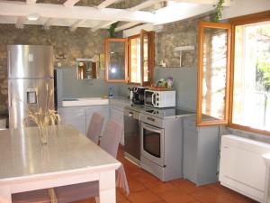 eine Küche mit einem Kühlschrank aus Edelstahl und einem Tisch in der Unterkunft Les Genêts in Fayence