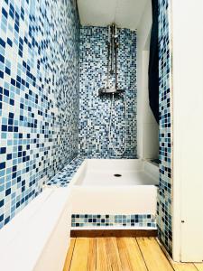 uma casa de banho com banheira e azulejos azuis em L Autre-Mans - Gare - Atypique - 4 Personnes - Rêve au Mans em Le Mans