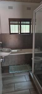 a bathroom with a sink and a tub and a toilet at Marina Beach Guest house in Southbroom