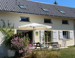 a house with a table and an umbrella and flowers at Gite Le Rucher in Lans-en-Vercors