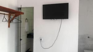 einen Flachbild-TV, der an einer weißen Wand hängt in der Unterkunft Ytamãní ll apartamentos in Santa Cruz Cabrália