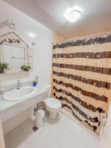 uma casa de banho com um lavatório, um WC e uma cortina de chuveiro. em Pé na Areia Praia do forte Cama Queen Wifi Netflix em Cabo Frio