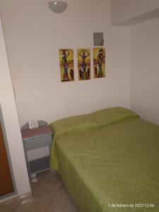 Monoambiente para 2 personas en Neuquen في نيوكين: غرفة نوم بسرير اخضر وثلاث صور على الحائط