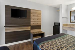 a hotel room with a bed and a flat screen tv at Bay Breeze Inn in Oakland