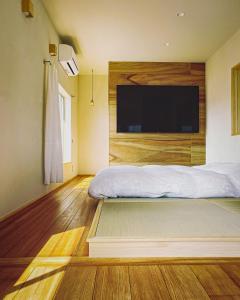 a bedroom with a bed with a large television on the wall at 暮らすように過ごすNagi unoport in Uno