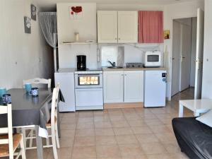 eine Küche mit weißen Geräten und einem Tisch in einem Zimmer in der Unterkunft Appartement Climatisé 2 Pièces avec Balcon et Garage Privatif à Cavalaire-sur-Mer - FR-1-226B-101 in Cavalaire-sur-Mer