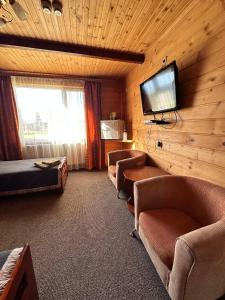 um quarto de hotel com uma televisão e um sofá e cadeiras em Котеджне містечко Мацеста 