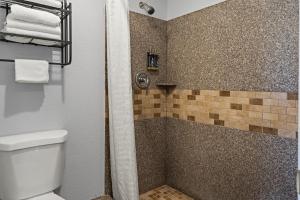 een badkamer met een douche, een toilet en handdoeken bij Bay Breeze Inn in Oakland