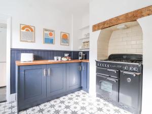 a kitchen with blue cabinets and a stove at Beautiful 4 Bed Beach House - Pool table & Parking in Pakefield