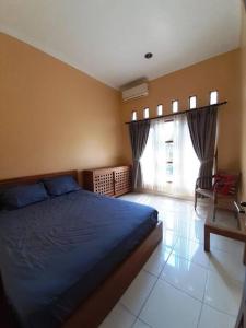 a bedroom with a blue bed and a window at Serasa Rumah in Yogyakarta