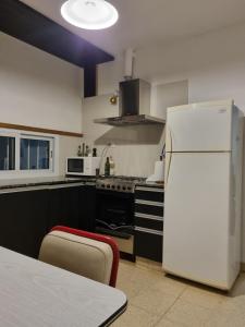 a kitchen with a white refrigerator and a table at Casa "La 310" in Ciudad Lujan de Cuyo