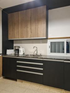 a kitchen with wooden cabinets and a sink at Casa "La 310" in Ciudad Lujan de Cuyo