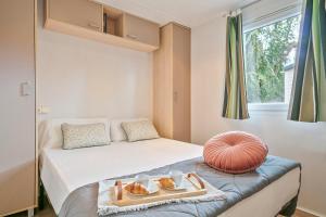 Un dormitorio con una cama con una bandeja de comida. en Càmping Castell Montgrí **** en L'Estartit